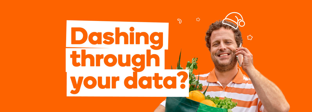 A smiling man holding Woolworths shopping bag full of produce in one hand and mobile phone in the other hand on orange background