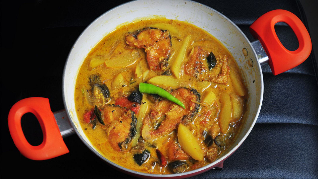 Fish curry with potatoes in red-handled pot