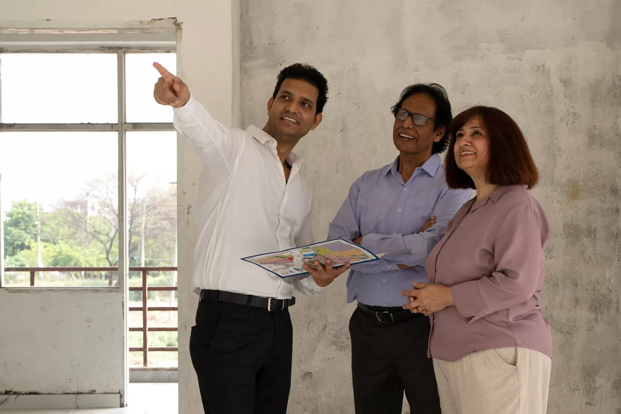 Indian Cheerful male contractor or builder showing with his parents in construction building