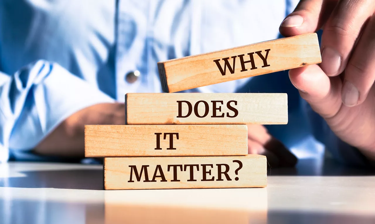 Close up on businessman holding a wooden block with "Why does it matter?" message