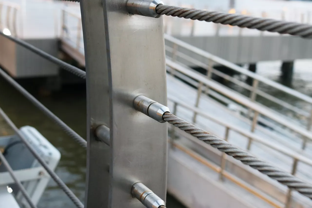 Stainless steel threaded stud joint with wire rope railing, selective focus.