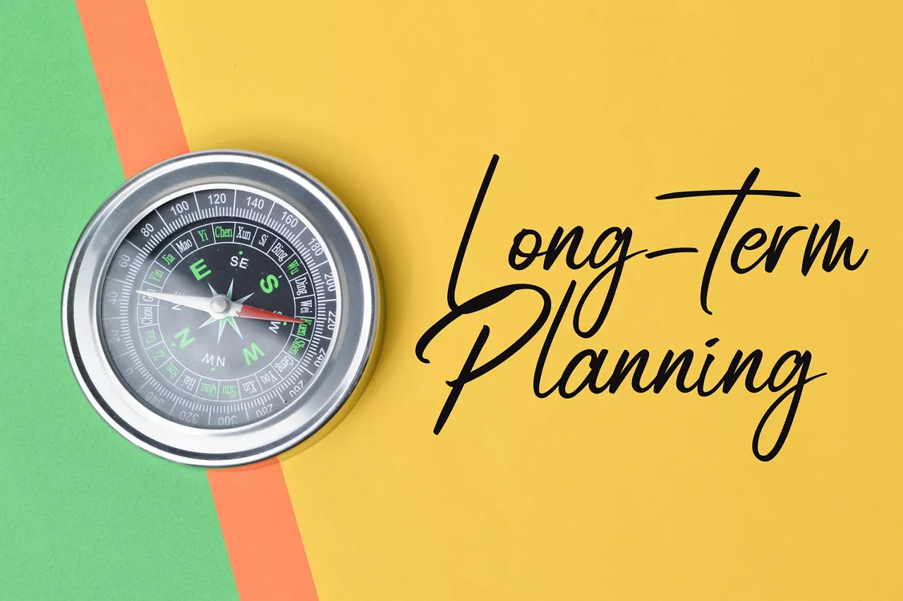 Top view of compass over colorful paper written with text LONG-TERM PLANNING. Business and education concept. 