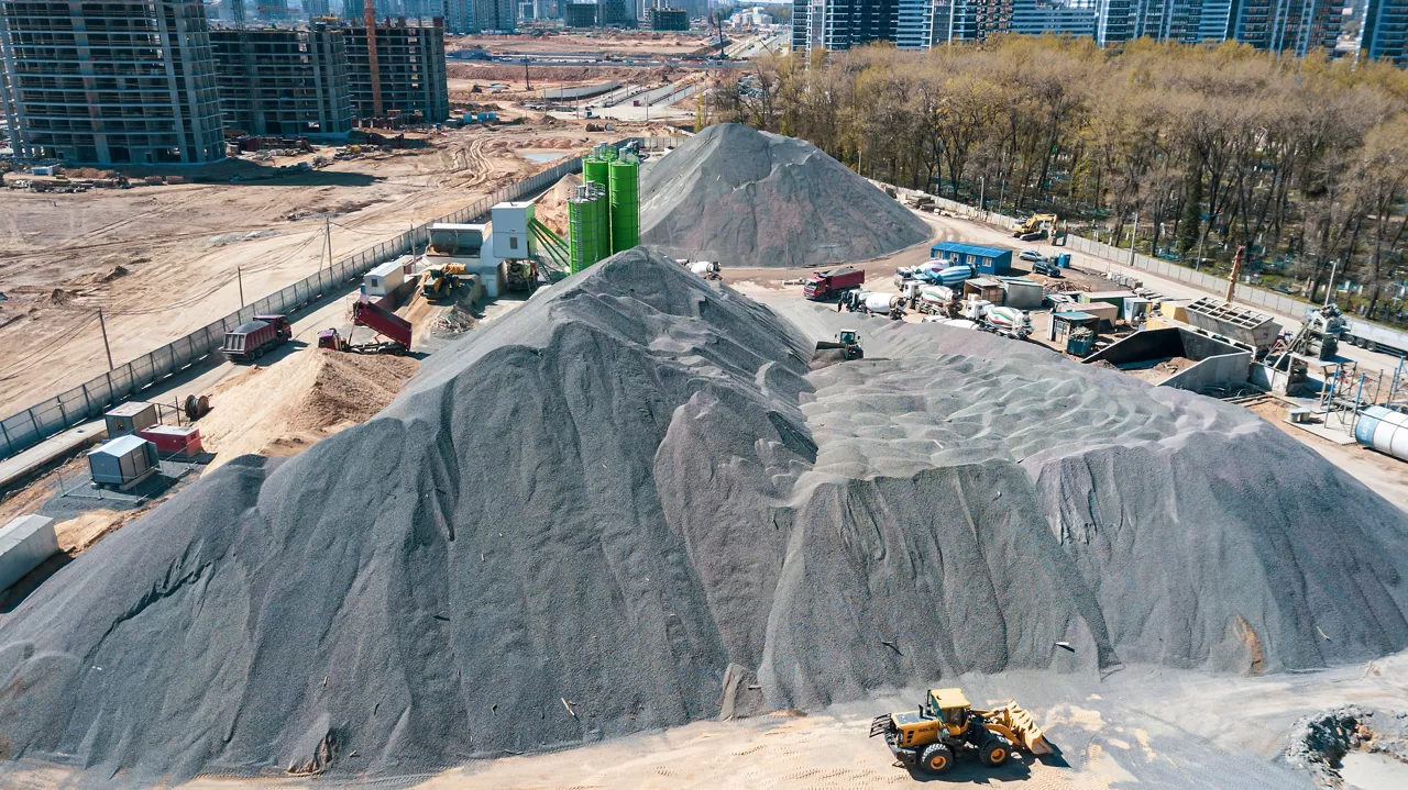 Aerial view of concrete and cement mortar plant. Concrete mixing silo for stone and sand. Bulk material storage site. Industrial concept and construction background.