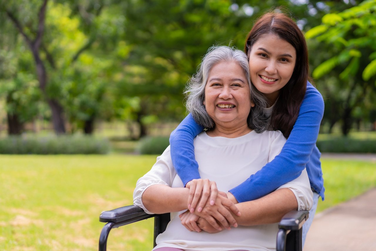 Woman wraps her hands around an elderly woman in a wheelchair