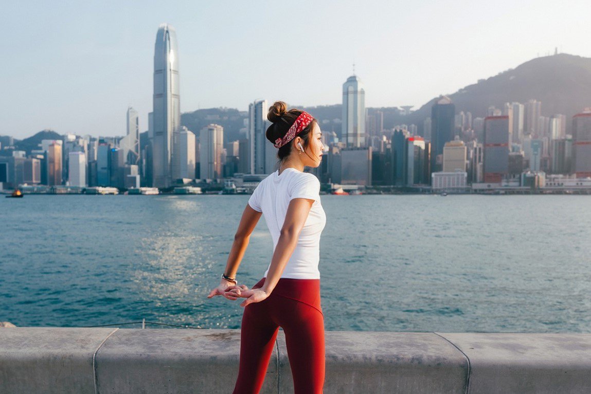 一名女性在香港海濱長廊伸展身體，展現積極健康的生活方式，呼應醫療保障重要性。