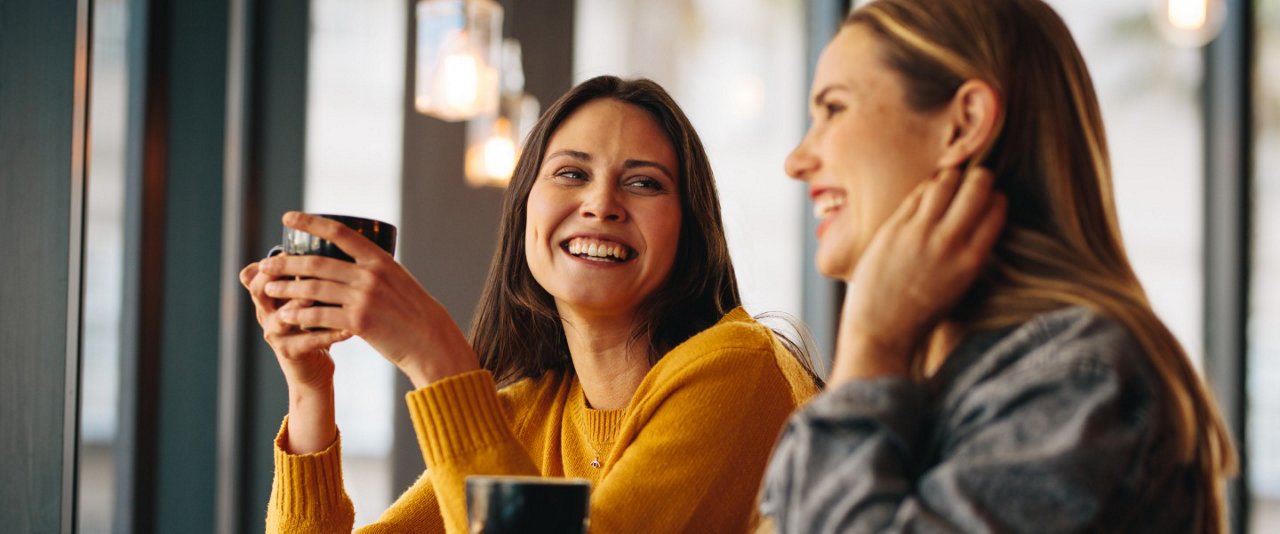 Two women seated at a table, enjoying a conversation over cups of coffee.