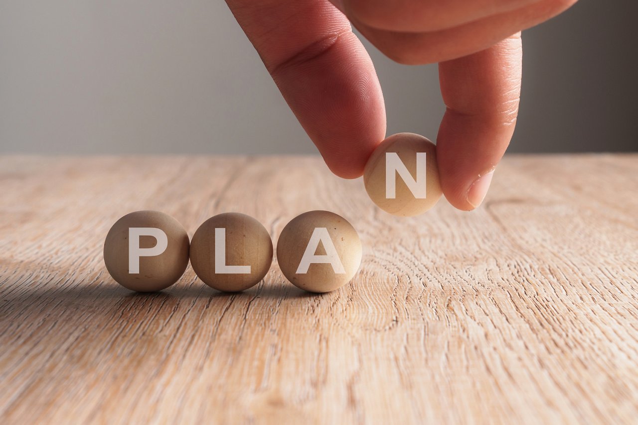 Hand putting on plan word written in wooden ball