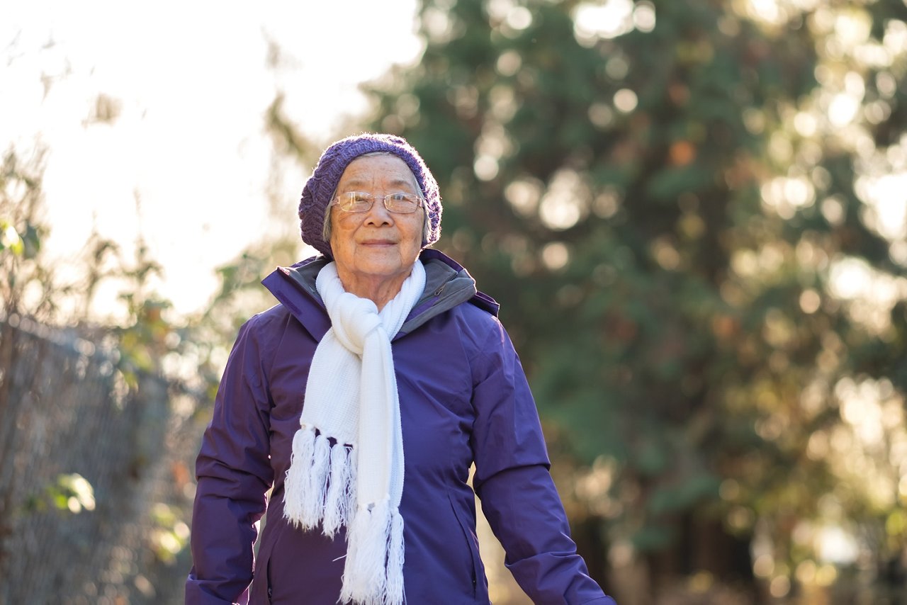 An elderly Asian woman begins her walk outdoors.