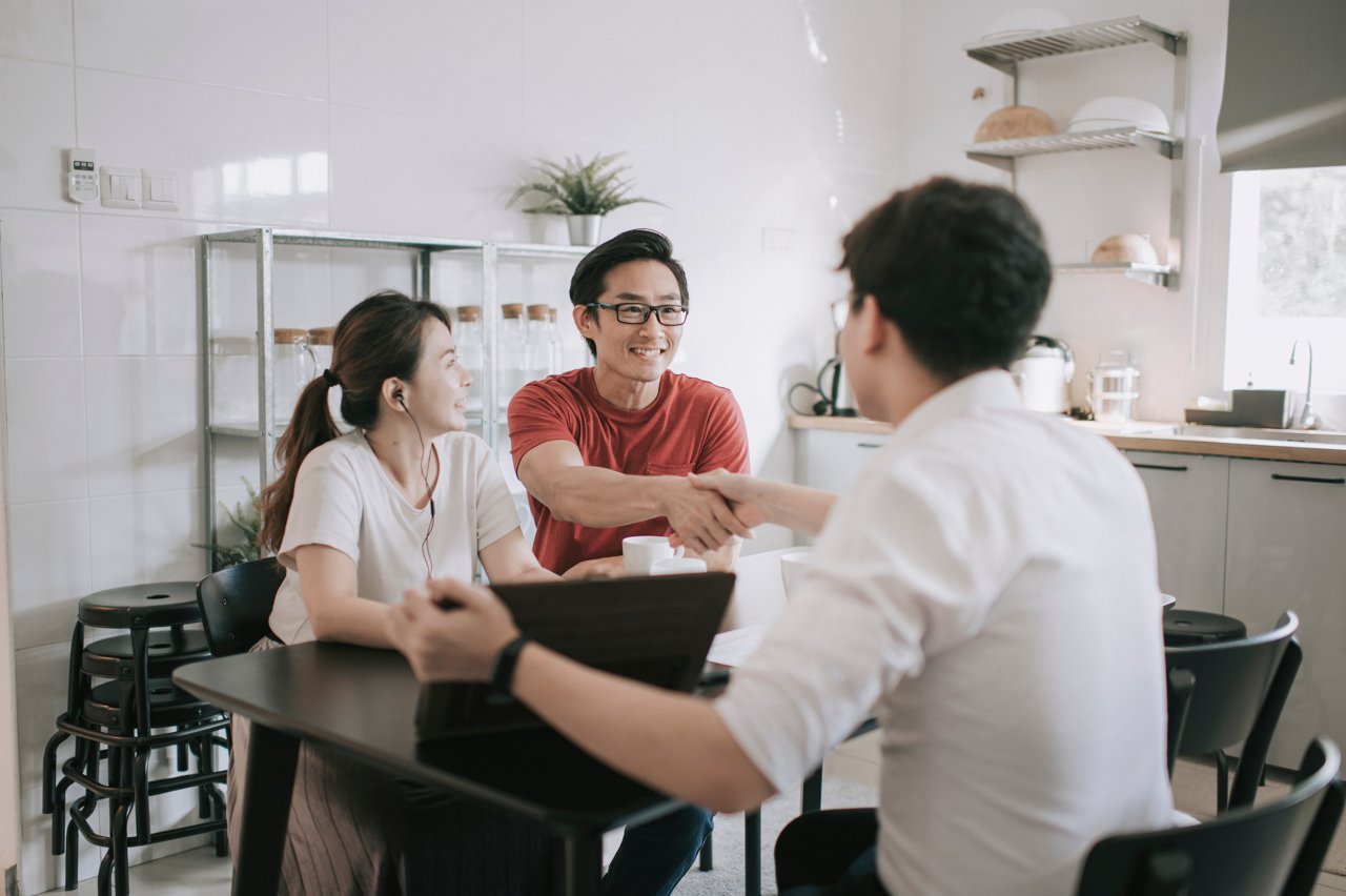 asian chinese insurance agent shake hands to his clients at their kitchen about the policies