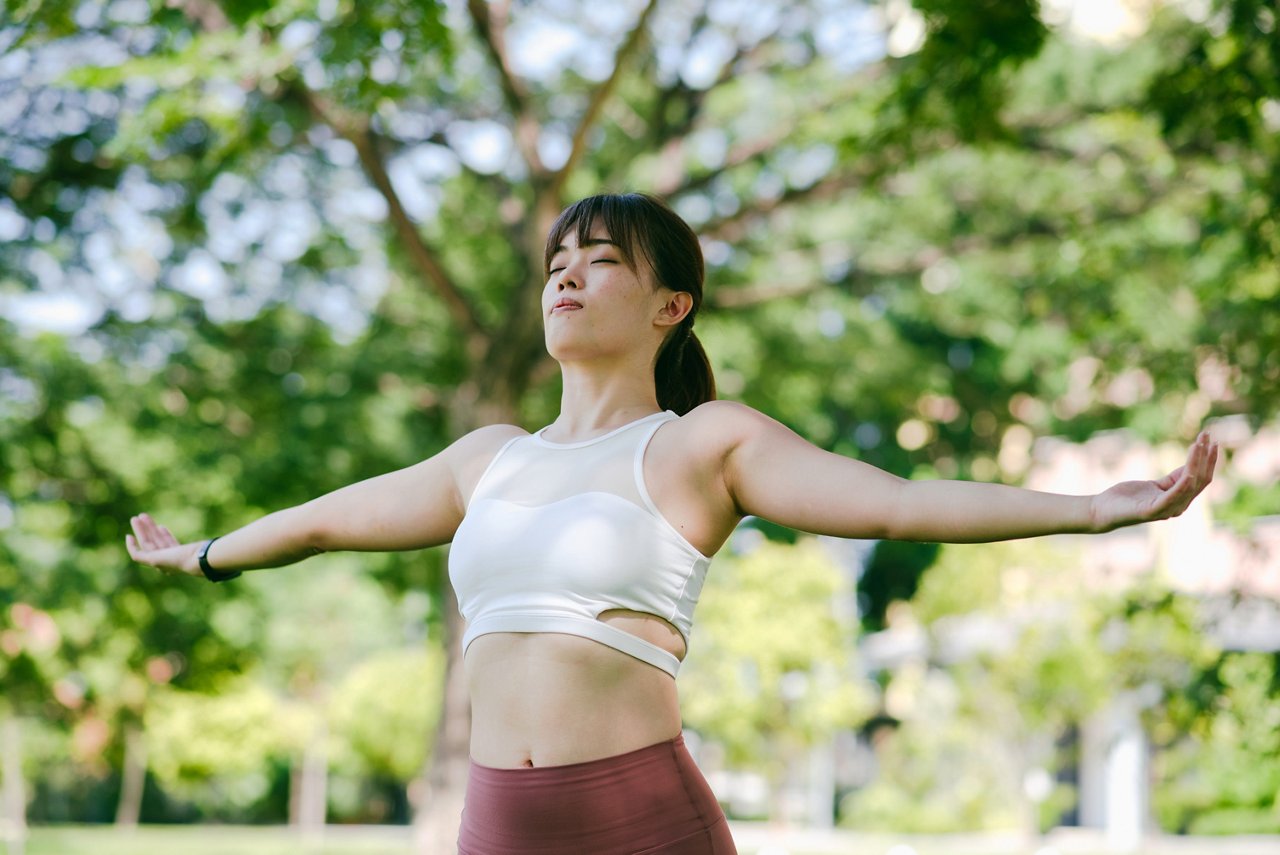 一位身穿運動裝的年輕女性在公園裡做拉伸運動。    