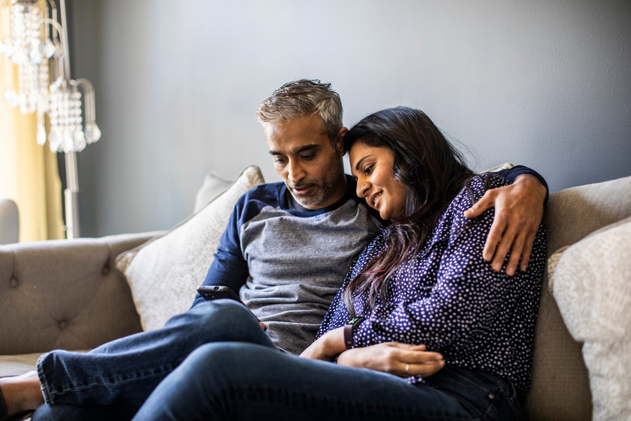 Man and woman smiling and looking at an iPad.