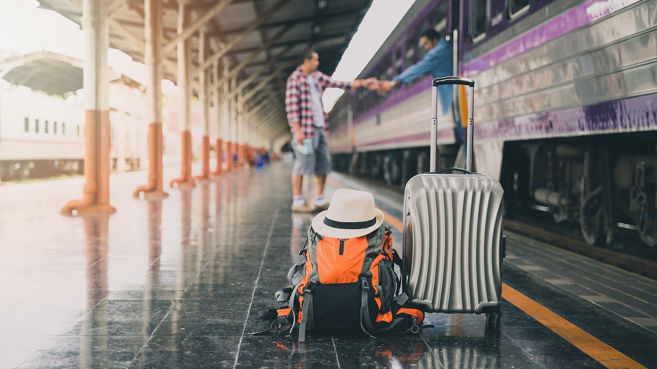 Backpack, luggage and hat over travellers at train station. Travel concept.