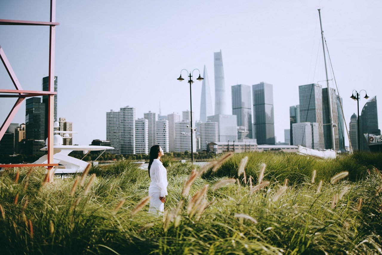 Woman stays still in a park that has a view of skyscrapers