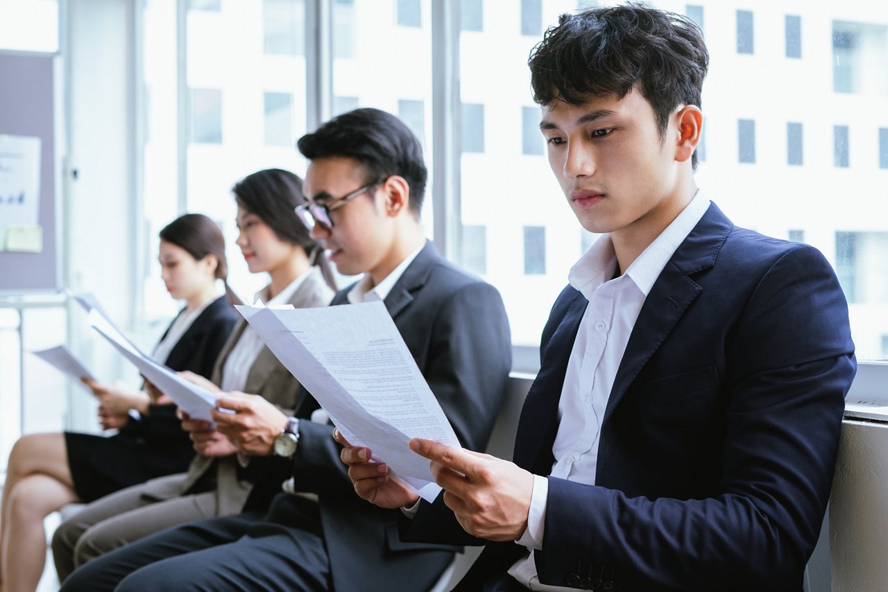 Young Asian men and women read documents while seated