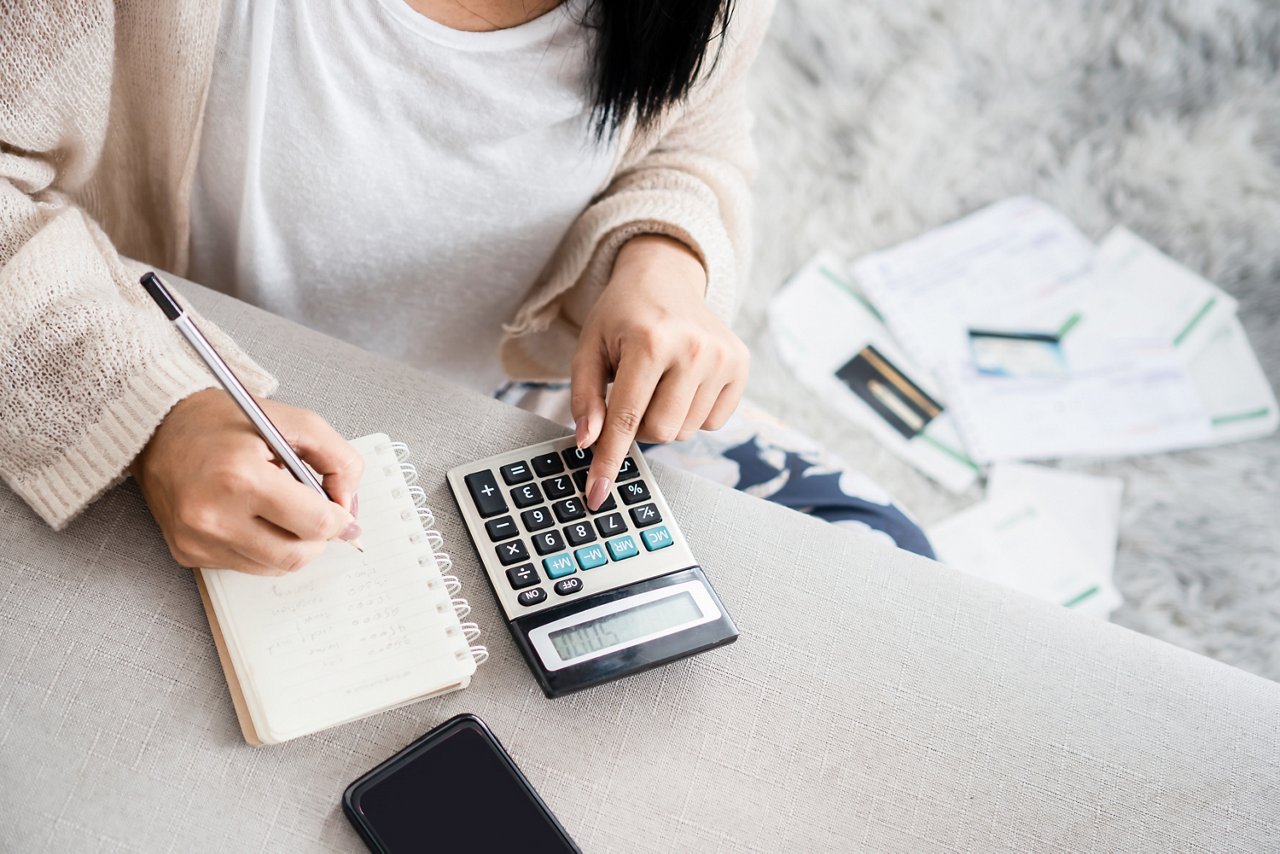 Woman writing in a notebook as she uses a calculator