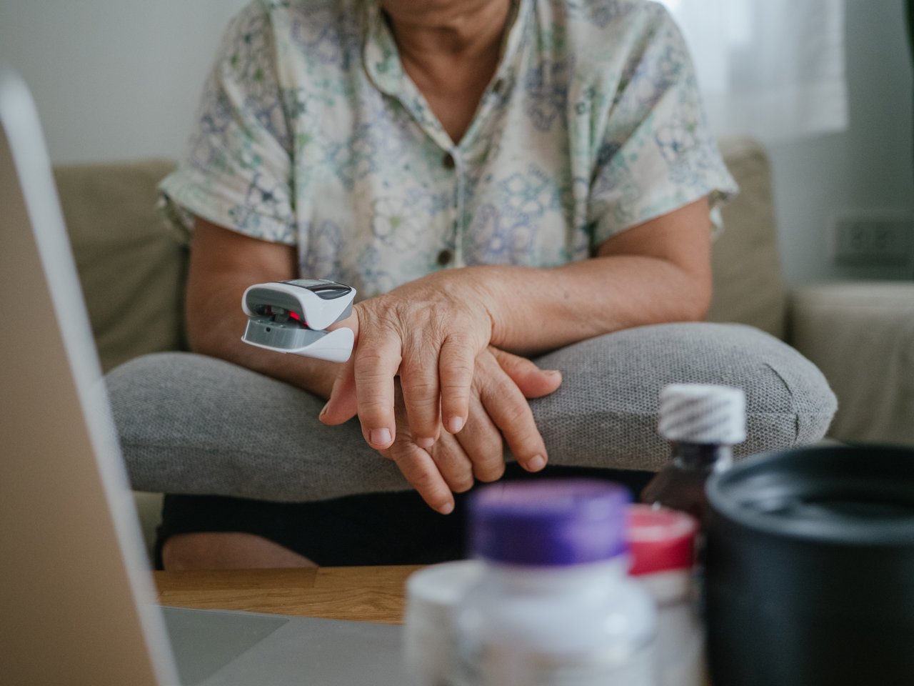 An elderly woman using a finger pulse oximeter at home