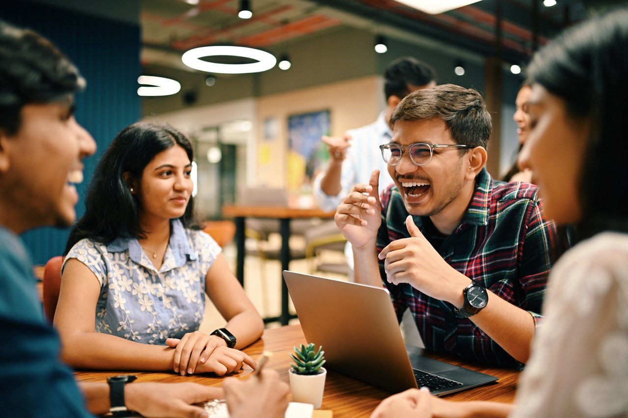 Work colleagues chat and laugh during a meeting.