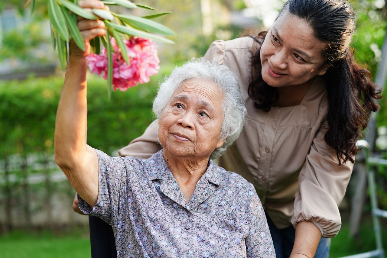 An old lady in a wheel chair holding a flower. 