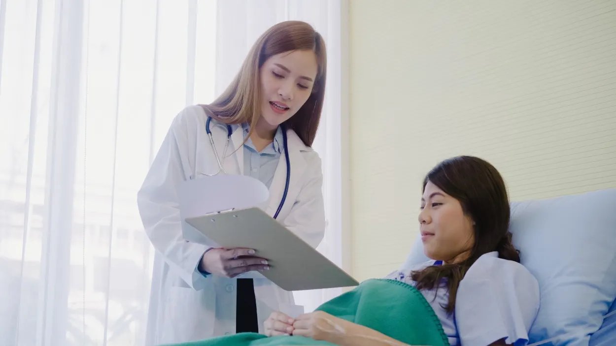 Dokter perempuan berdiskusi dengan pasien mengenai kondisi kesehatannya, menunjukkan pentingnya perlindungan dari asuransi penyakit kritis