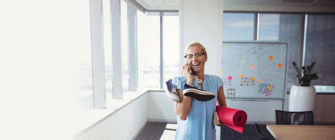 Middle aged woman in office carrying sneakers and yoga mat
