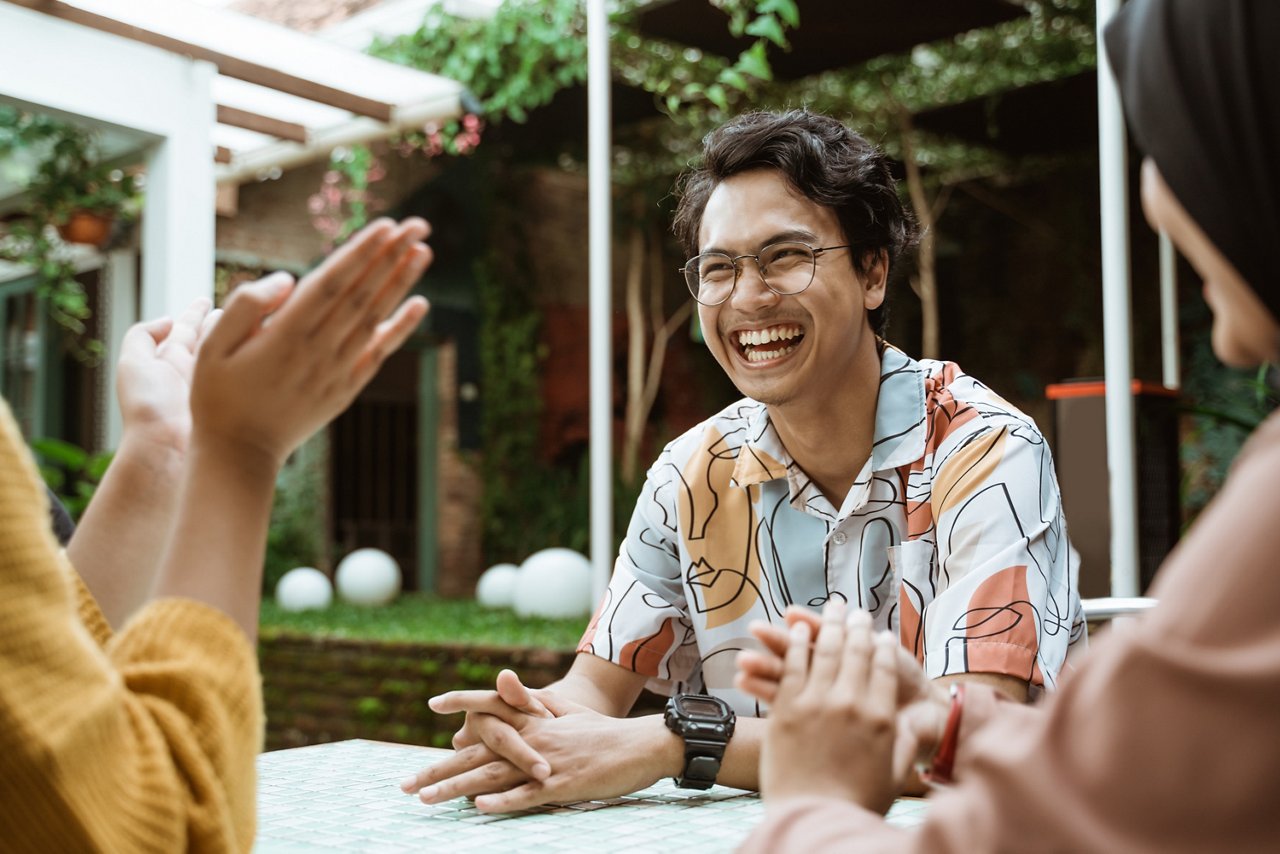 handsome students laughing while chatting while hanging out with friends in coffee shops