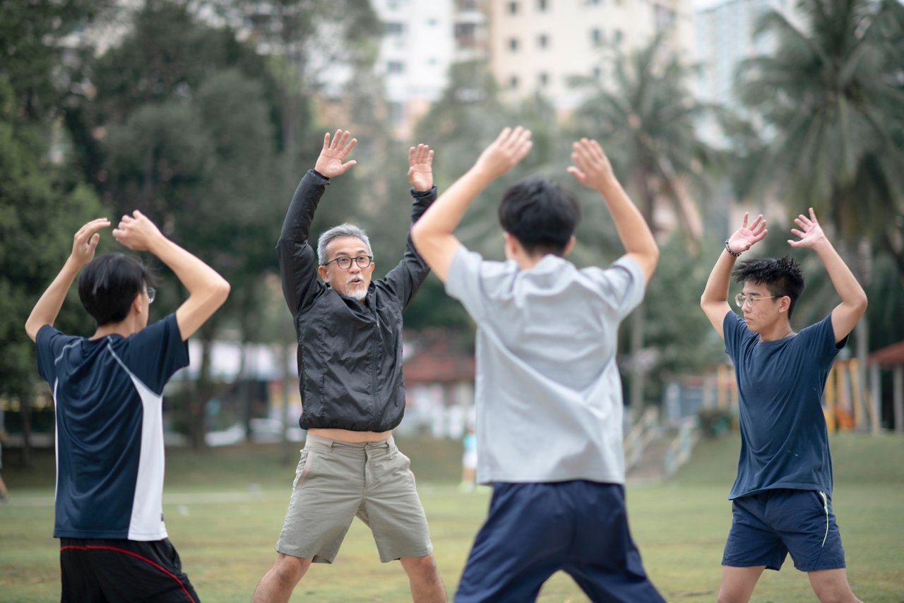 Group of Asian men of various ages doing jumping jacks