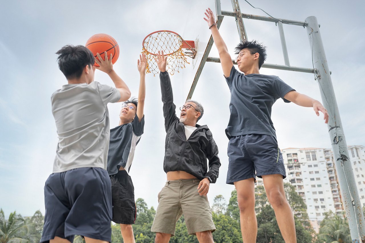 Men from different age groups playing basketball at an outdoor park