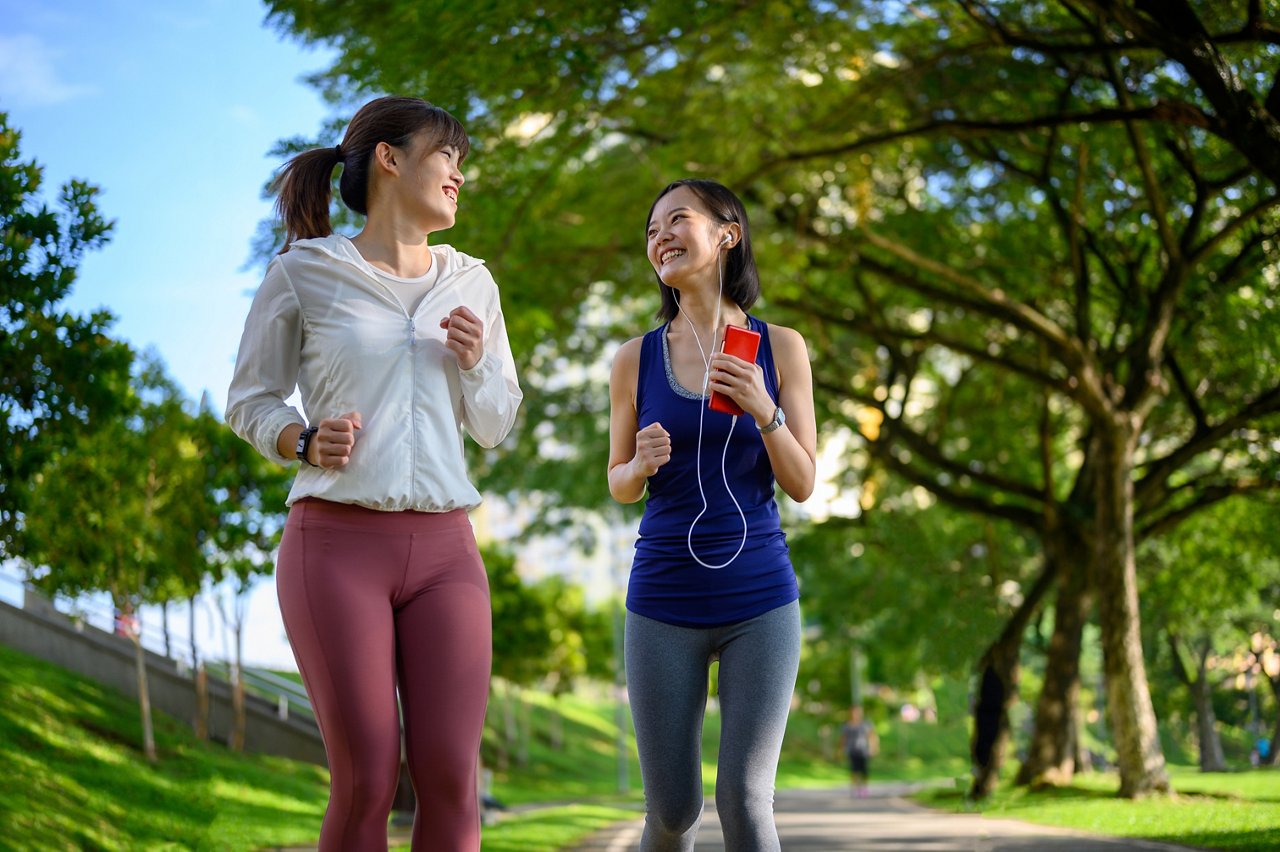 Two Asian women brisk walking together in the park
