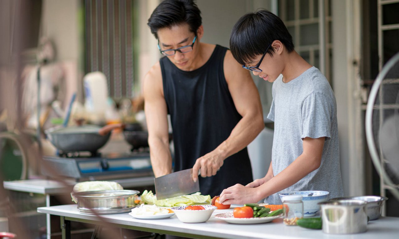 一位父親正在與年輕的兒子正在準備食材，為晚餐做好準備。