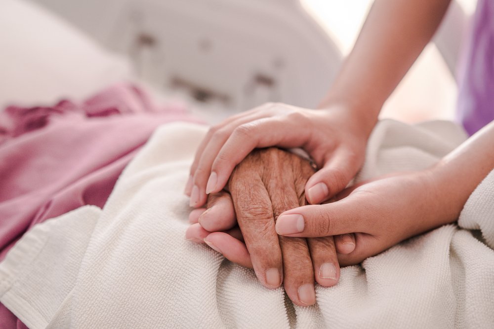 Closeup of loving couple holding hands while sick , Hand of young woman touching old woman in hospital