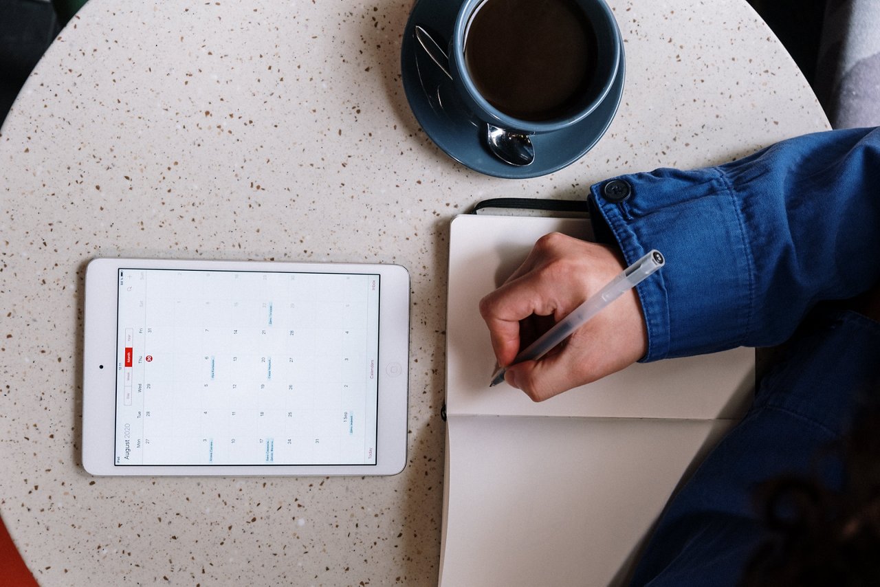 Top view of a man planning his schedule on his notebook and tablet. 