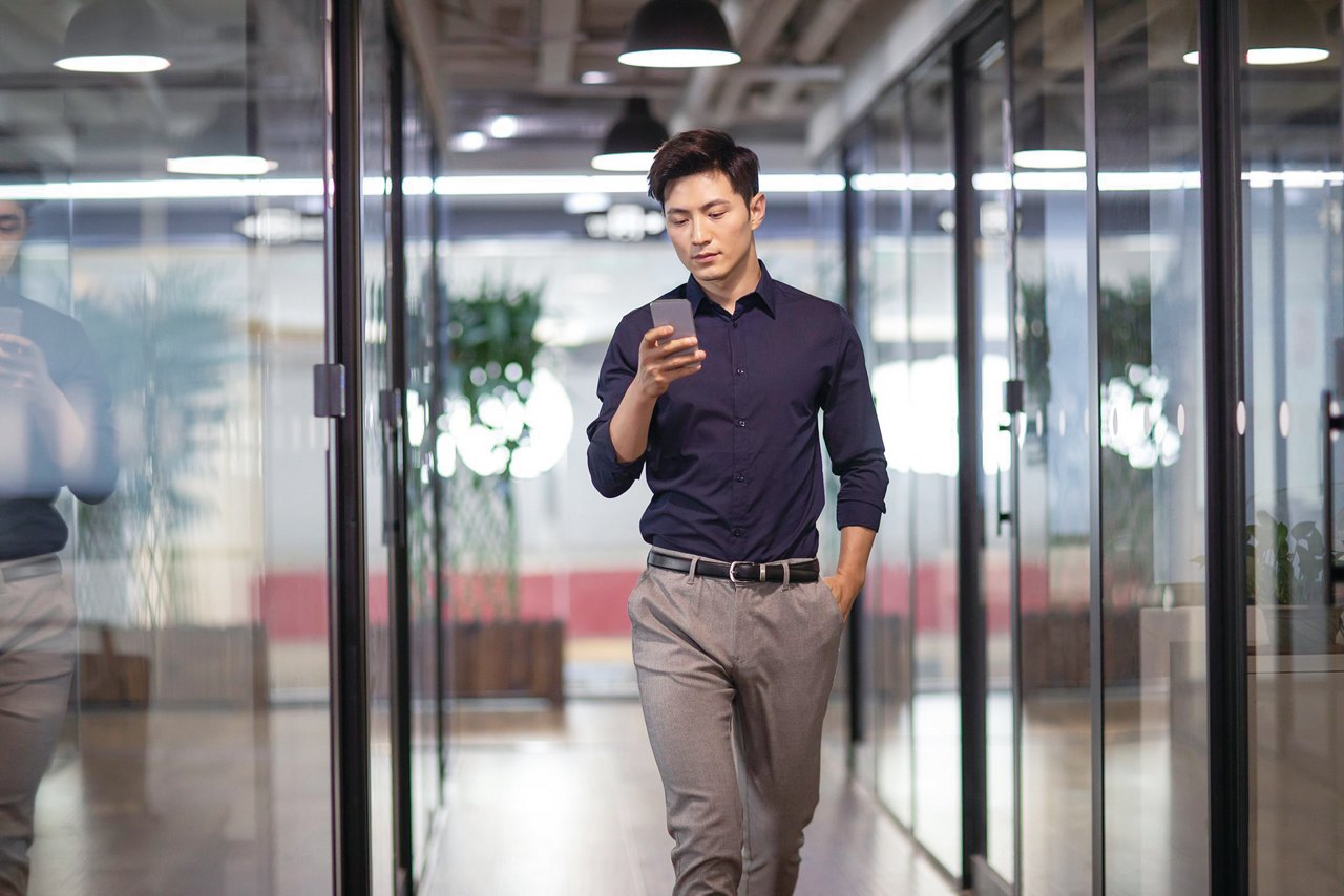 Confident young Chinese businessman using smart phone