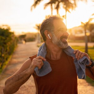 A man in gym attire smiles while holding a towel