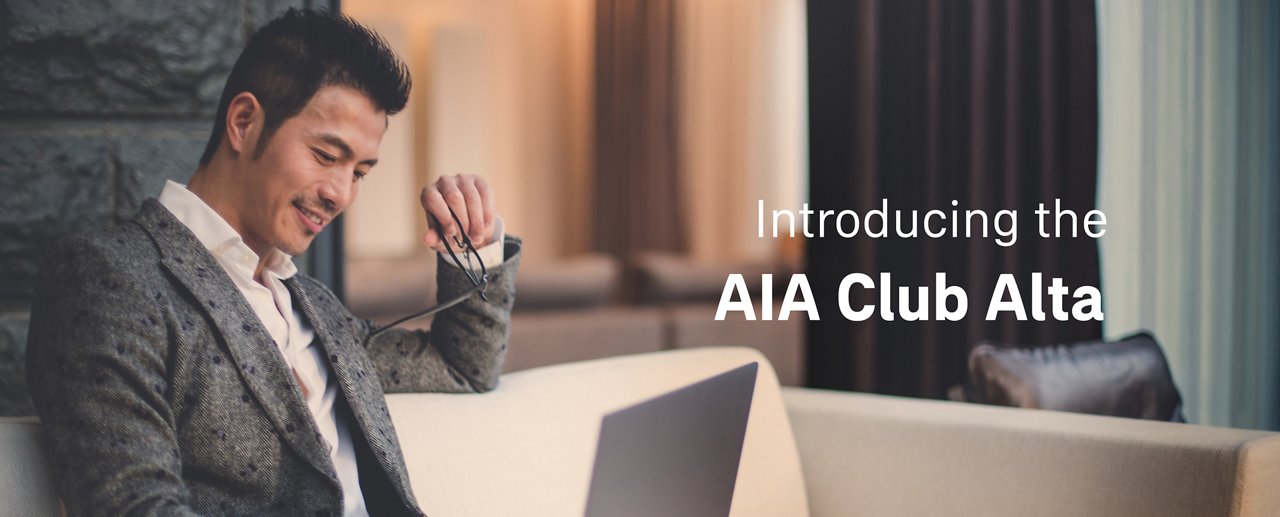 Relaxed businessman on sofa using laptop. With AIA Club Alta's privileges, he elevates overall well-being by aligning mind, body and prosperity.