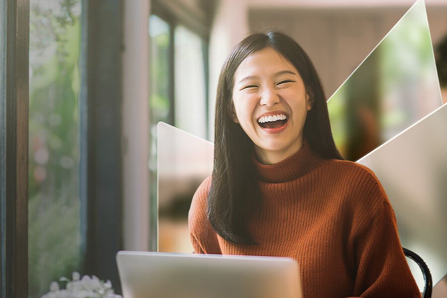 Lovely Asian girl and mother celebrating birthday with friends / family by having a virtual birthday party at home. Enjoying birthday celebration in front of the laptop during pandemic. Practicing social distancing. Birthday lifestyle theme