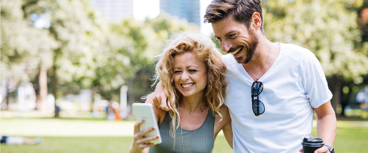 Couple ourdoors smile looking at phone