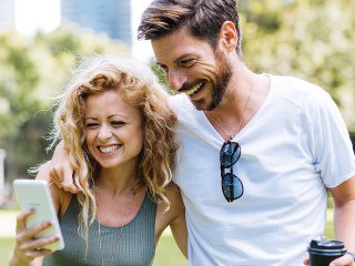 Couple smiling while looking at phone