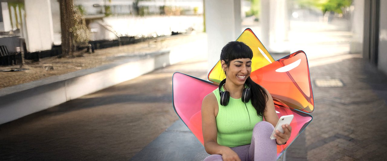 A woman sits on the ground, holding a vibrant, colorful umbrella above her
