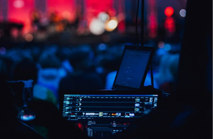 A stage featuring a monitor and microphone, set before an engaged audience.