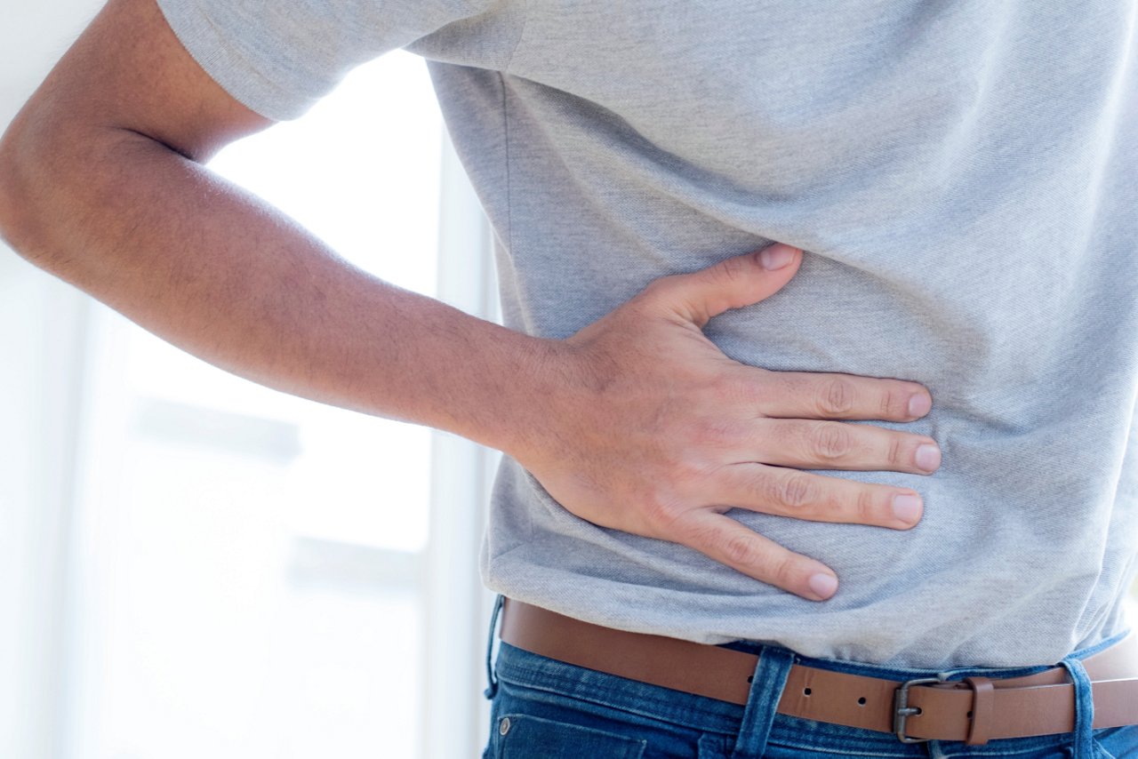 A man is pressing the right side of his abdomen because of pain from his appendix.