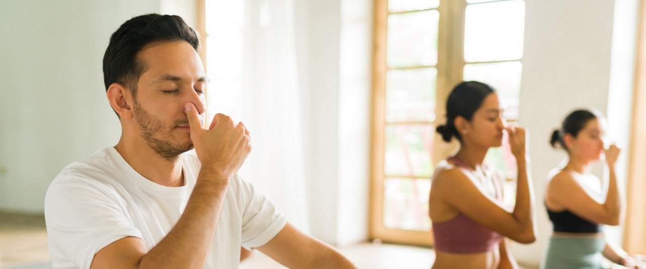 In a yoga class, a man practices breathing through his nose.