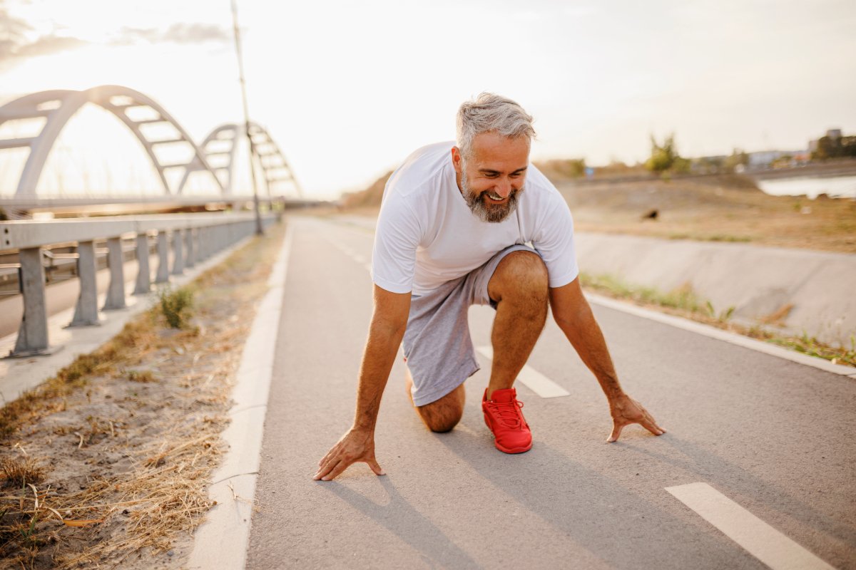 A man kneels on the road, demonstrating determination while engaged in a running activity.