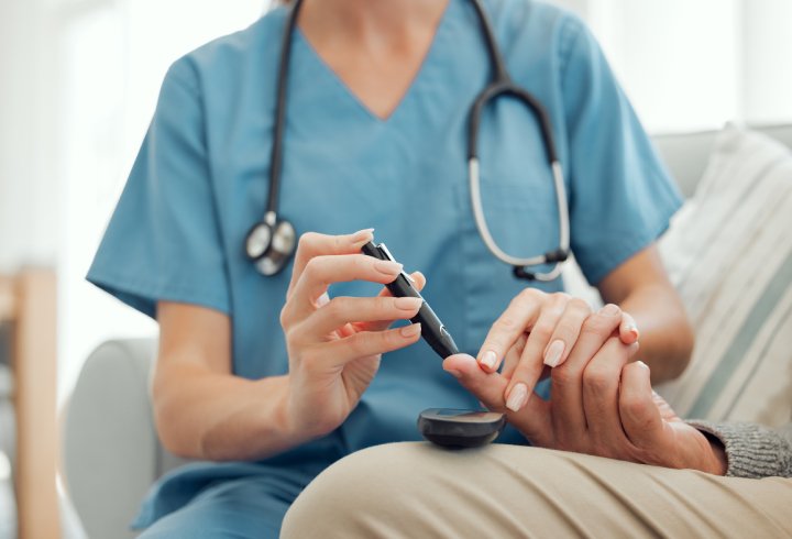 Healthcare professional checking a patient's blood sugar level using a finger-prick test for diabetes screening.