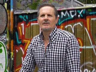 Middle-aged man sitting on chair with grafitti background