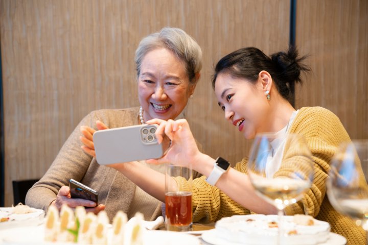 一個母親與女兒學習使用手機自拍