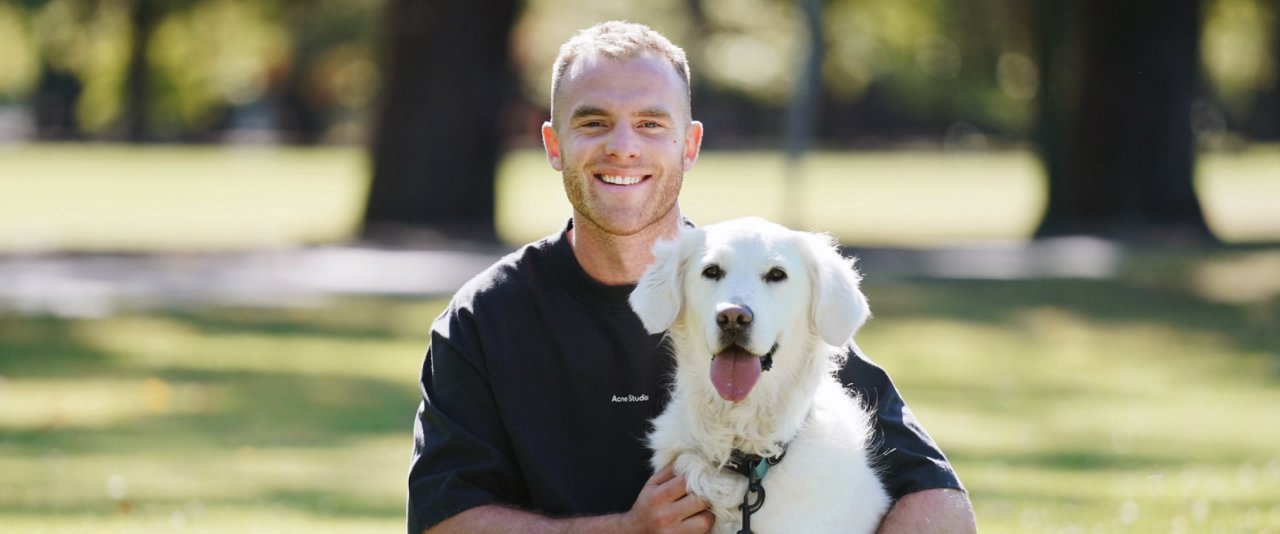 A man sits on the grass, enjoying the company of his dog beside him