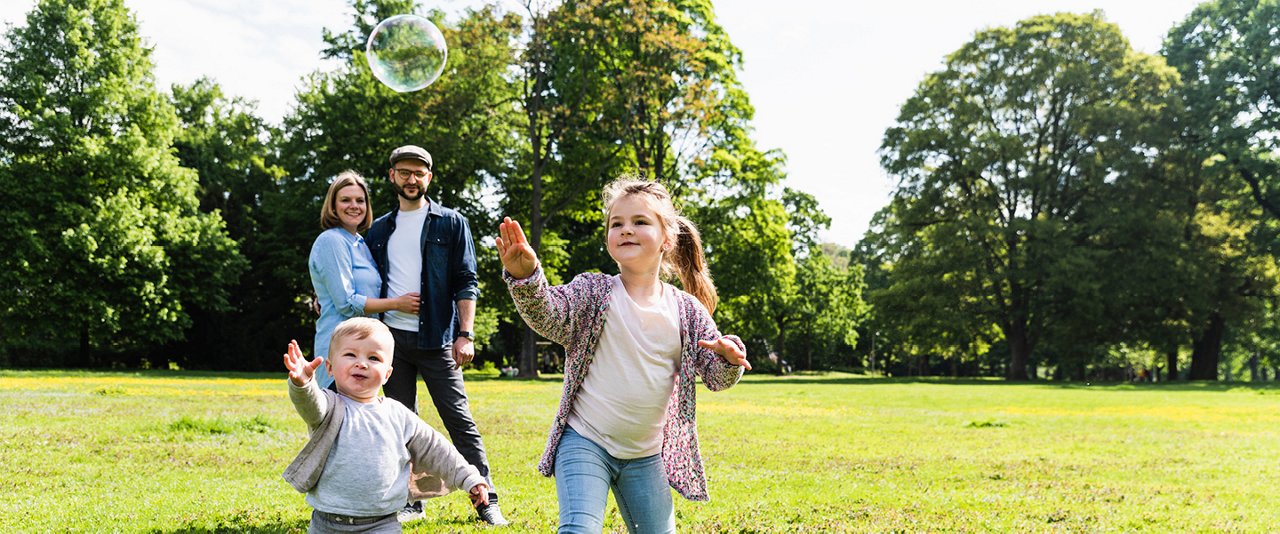 Family outdoors with kids chasing bubbles