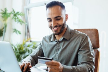 Man on laptop looking at credit card