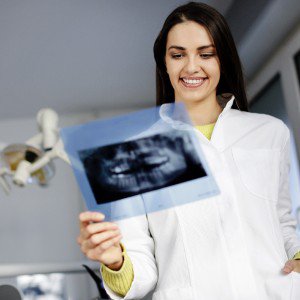 A dentist in a white coat examines an X-ray