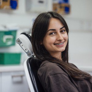 A woman smiles while seated in a dental chair